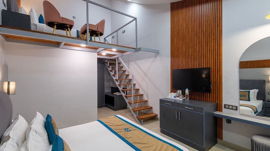 Spring Duplex Room at DLS Spring  Valley resort Dharamshala featuring a king bed table, chairs and stairs leading to second story